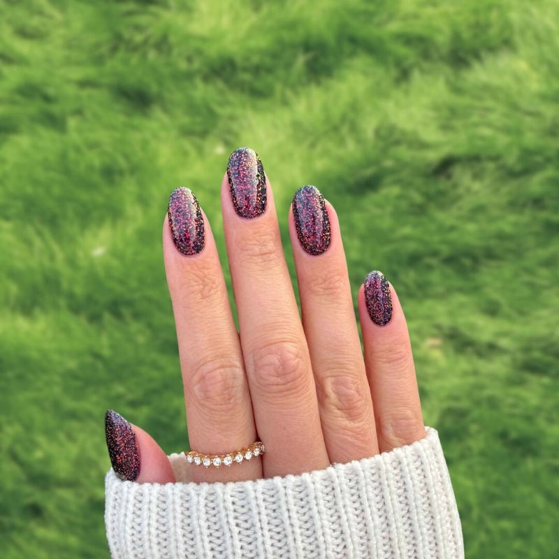 Close-up of Black Sparkle Dip Powder with Red and Gold Flakes for Nails